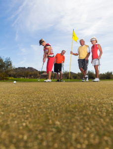 Friends putting on a golf putting green